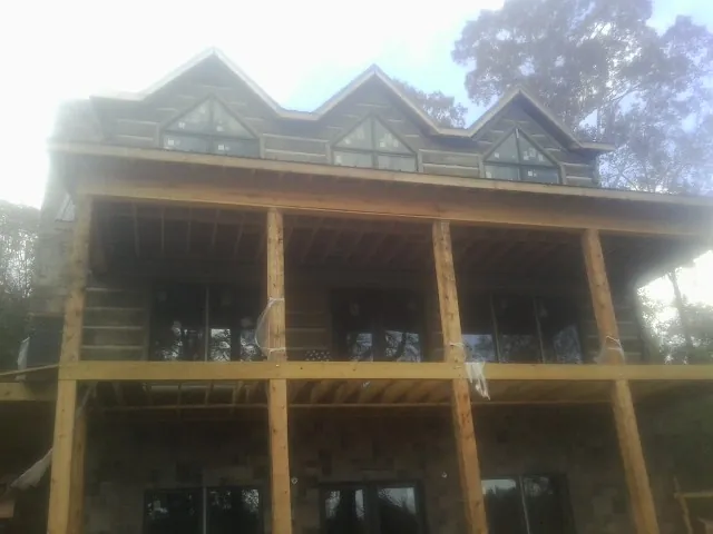 Dormers and porch framing on a large log home under construction — Roof Coating work by our crew in Oakhurst