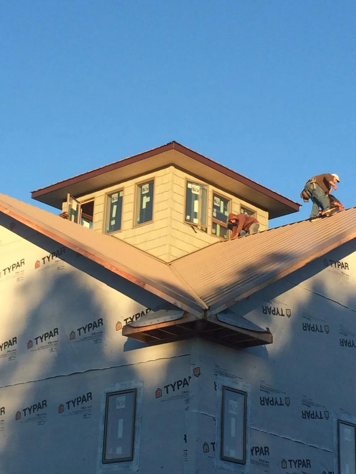 Roofers working around a rooftop cupola on a new metal roof at sunset — Roof Waterproofing in Oakhurst by Roofing Brothers